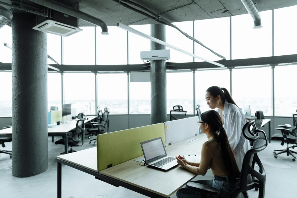 Two Asian women collaborating in a modern office environment focused on teamwork and innovation.